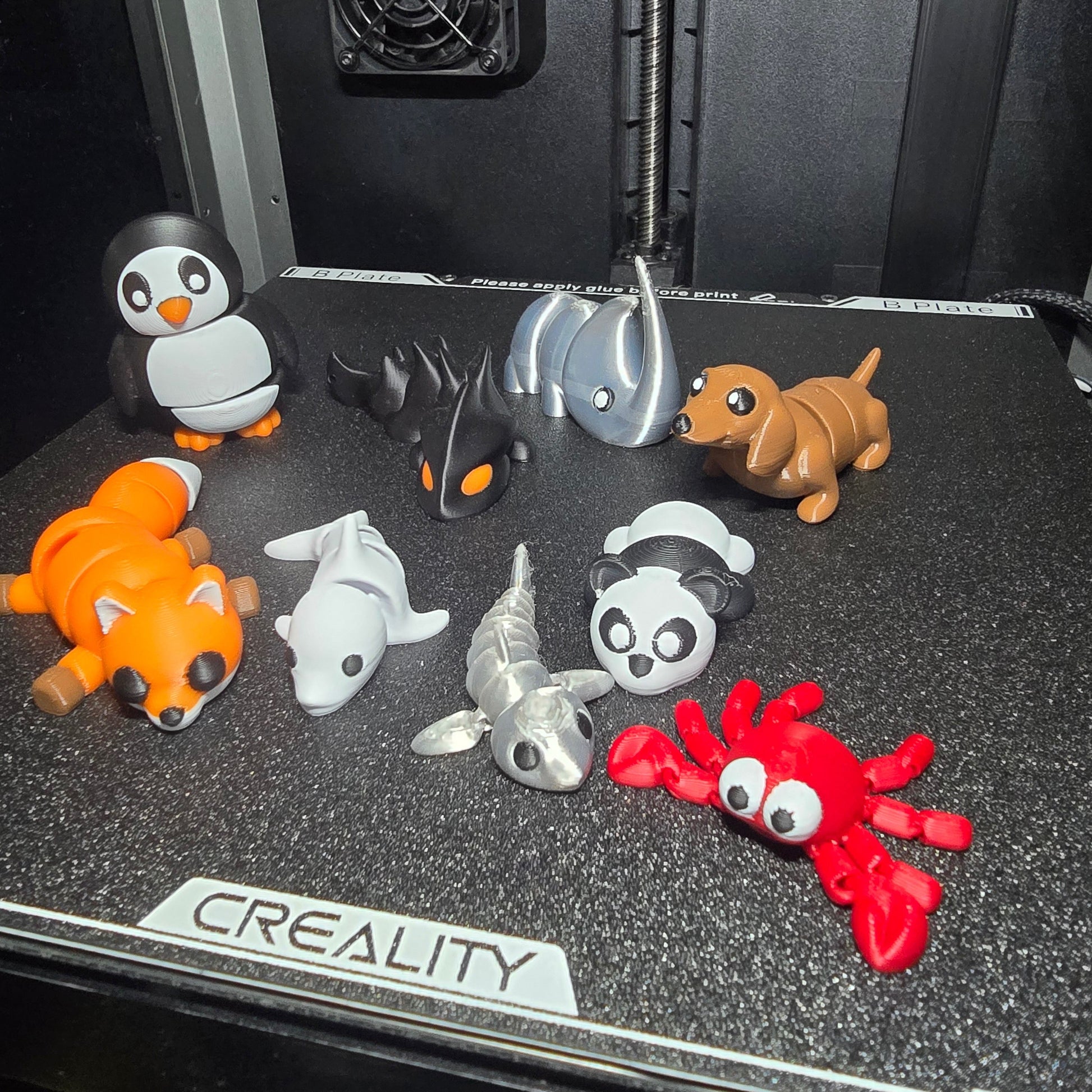 Collection of small 3D-printed animals on a Creality 3D printer bed.