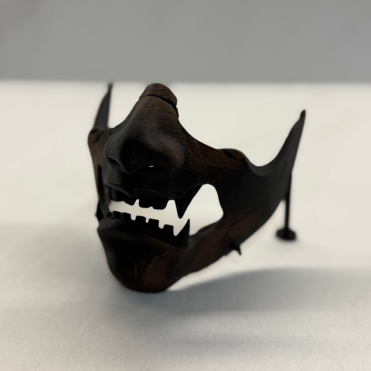 Black mask with a shark-like design on a white surface