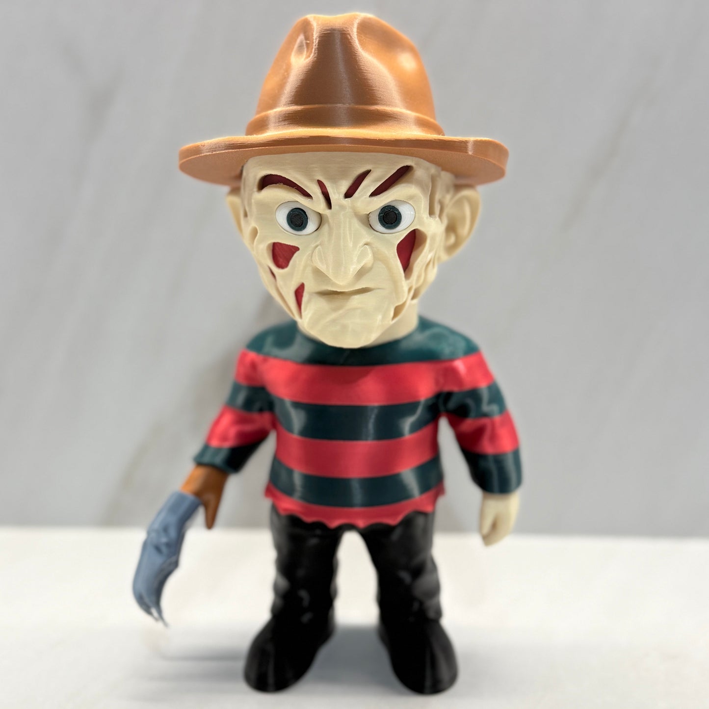Toy figure of a character with a brown hat and red and black striped shirt on a white background