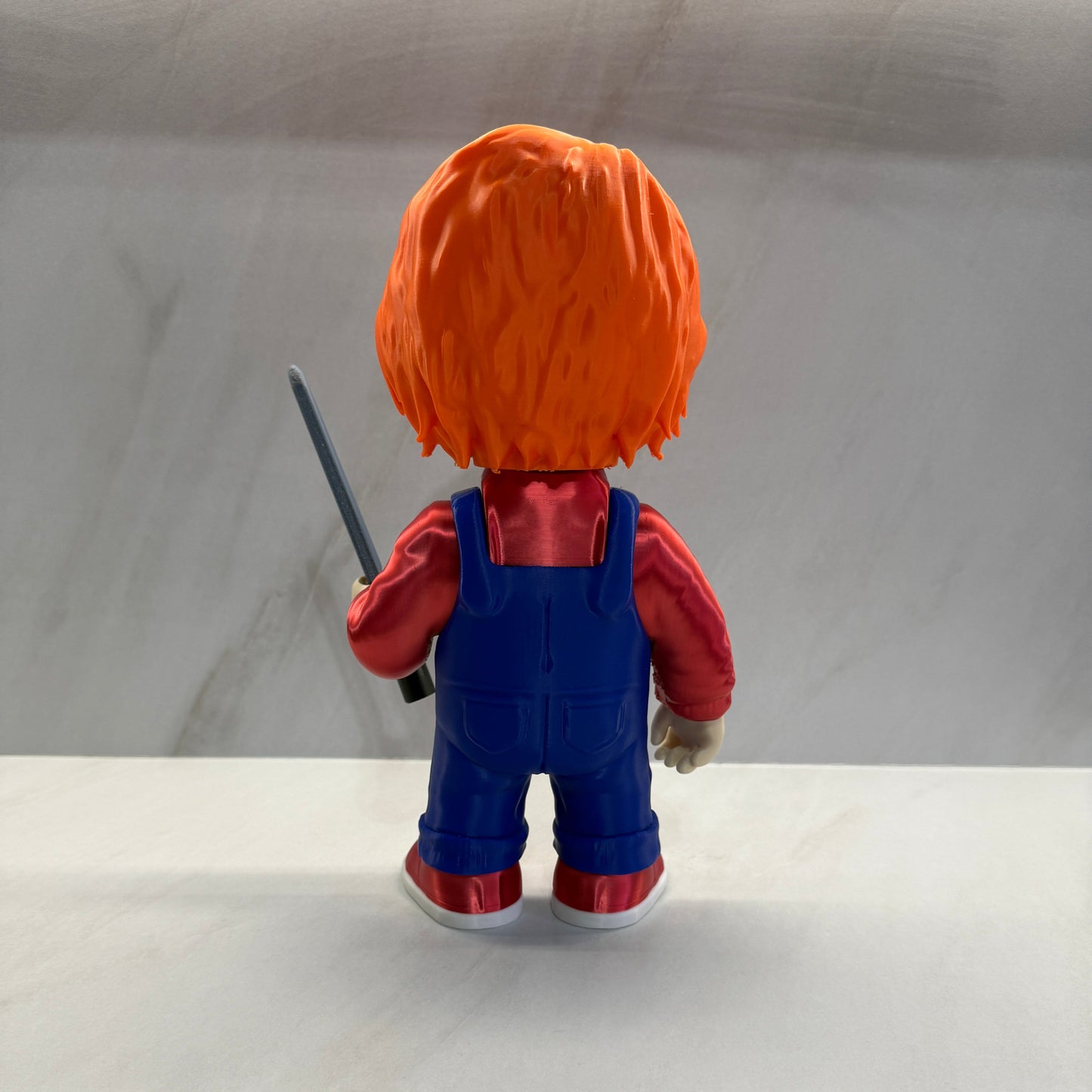 Toy figure of a character with an orange head and blue body against a plain background