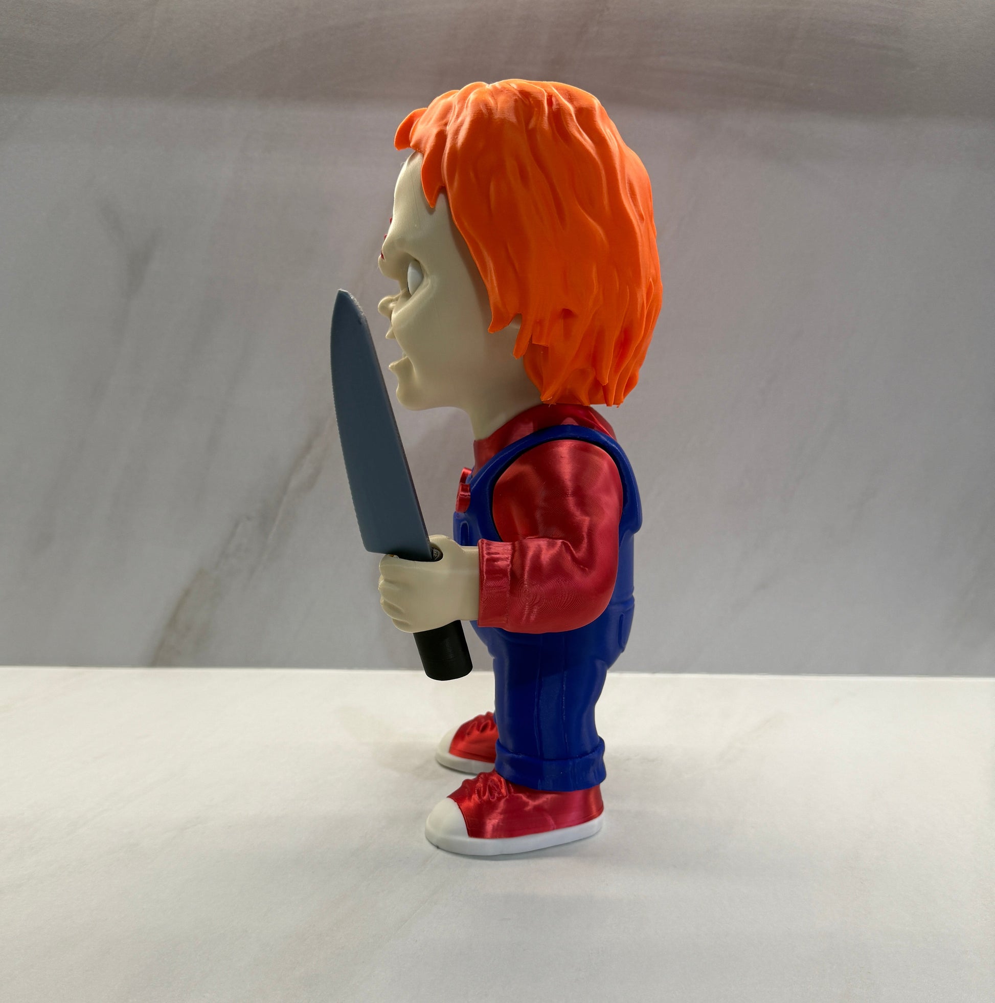 Toy figure with orange hair and blue outfit holding a knife on a white background