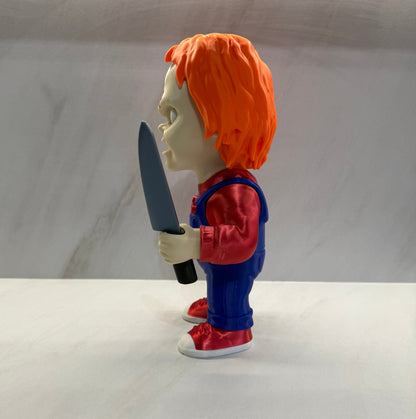 Toy figure with orange hair and blue outfit holding a knife on a white background