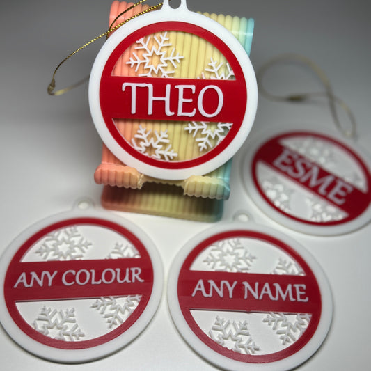 Decorative name tags with 'THEO' and 'ESME' printed on them, featuring a snowflake design.