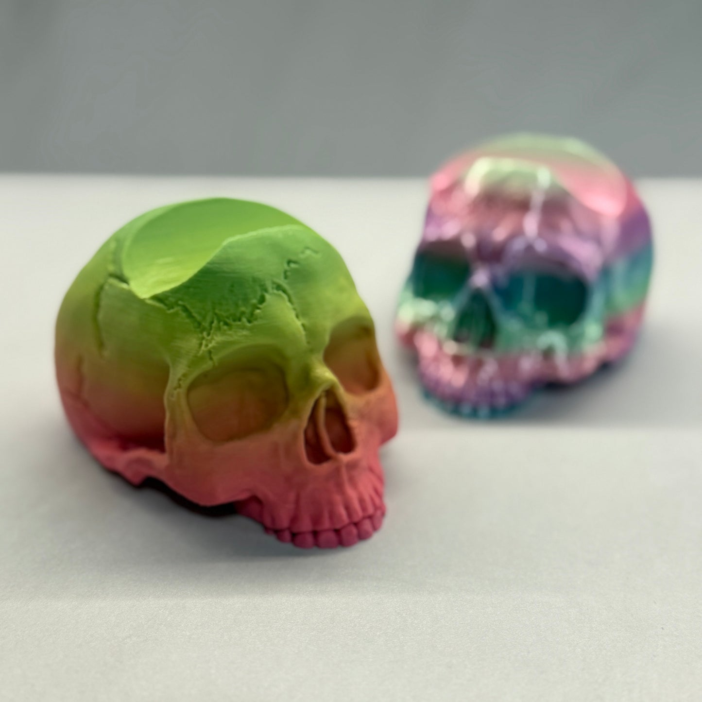 Two colorful skull-shaped objects on a white surface with a gray background - Controller Holder