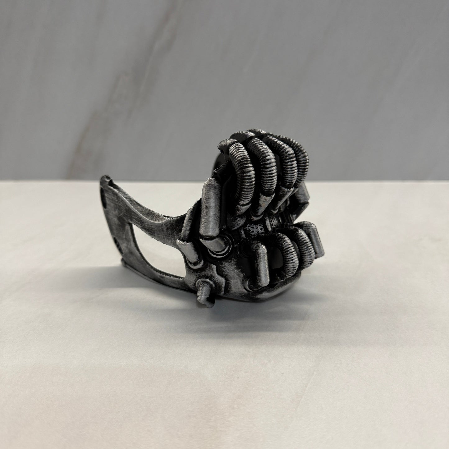 Metallic claw-like object attached to a white surface