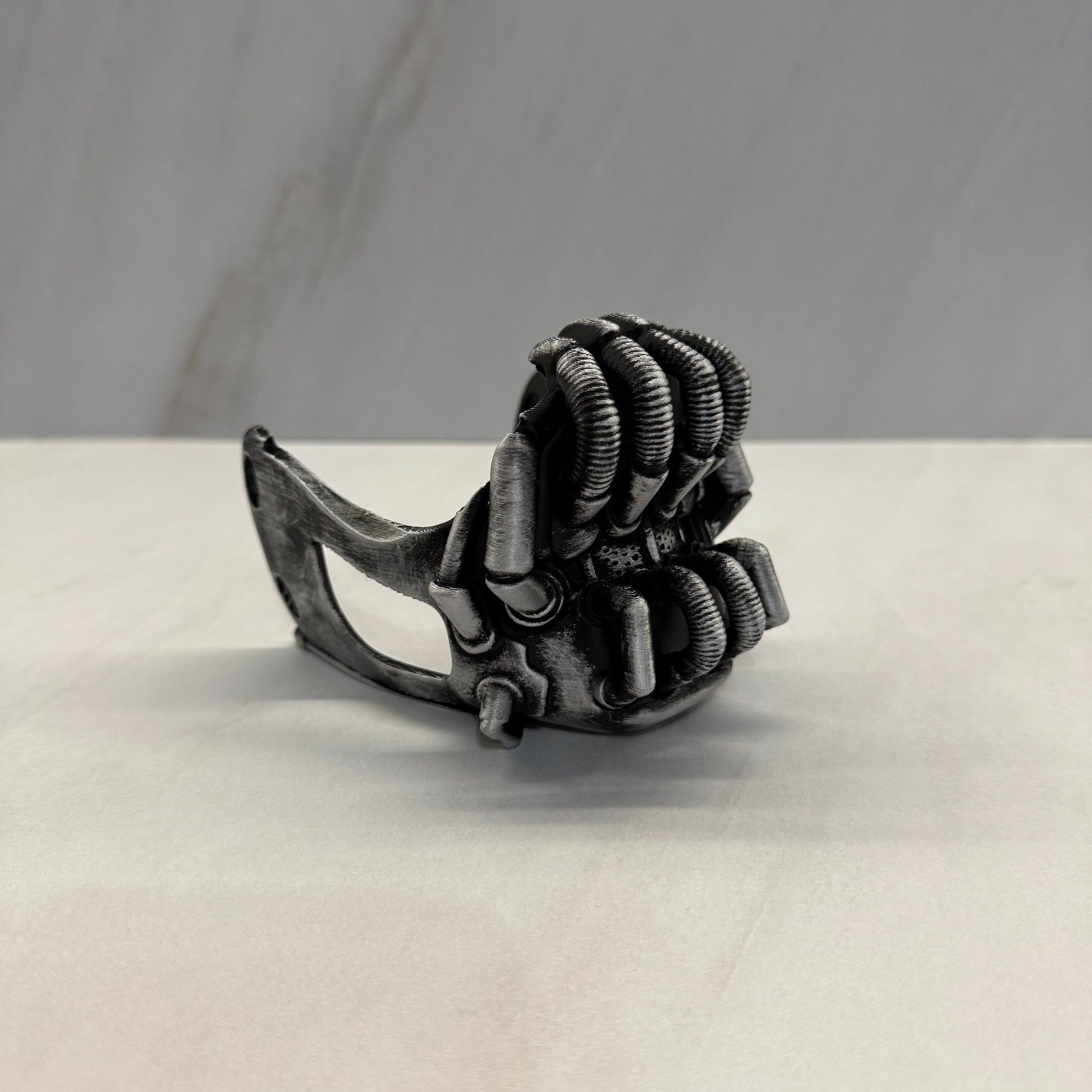 Metallic claw-like object attached to a white surface