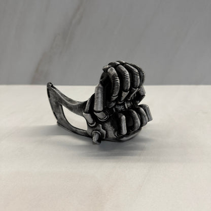 Metallic claw-like object attached to a white surface