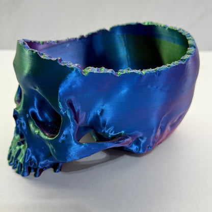 Metallic blue and green skull sculpture on a white background