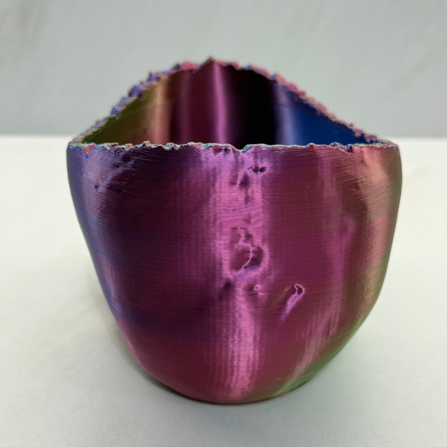 Metallic purple and green object on a white background