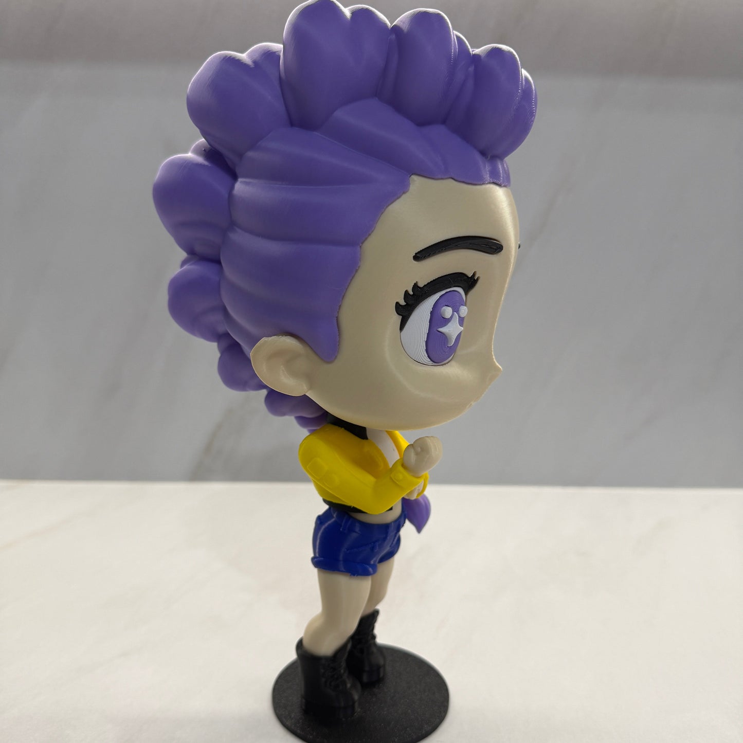 Purple character with a yellow bow attached to a white wall