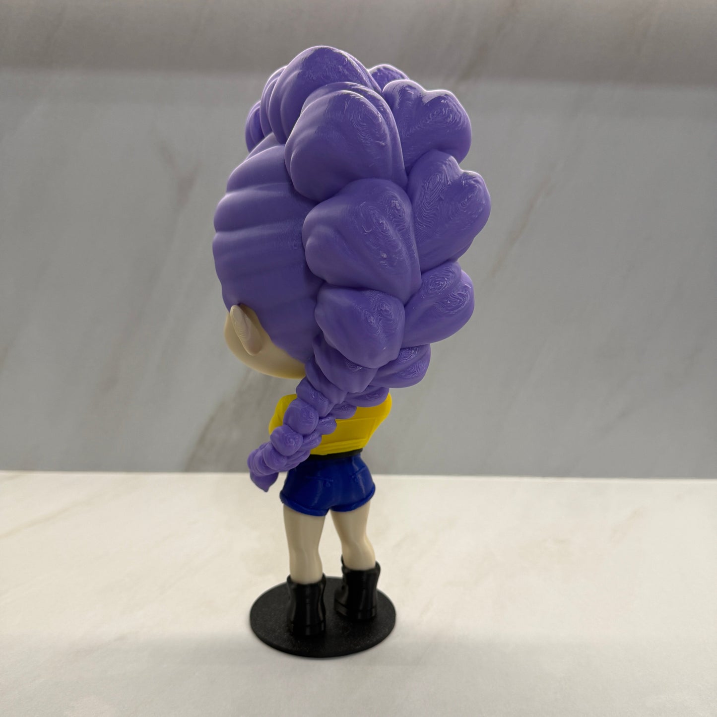 Purple bath sponge with a handle attached to a white wall