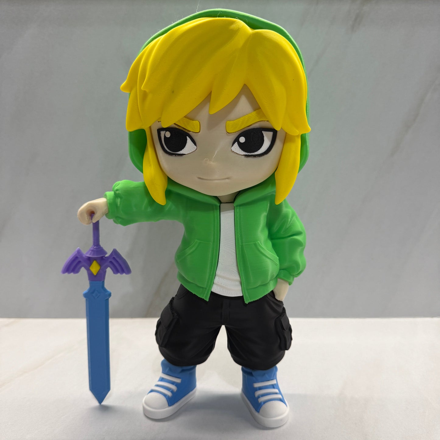 Toy figure of a character with green hoodie and yellow hair holding a sword on a white background