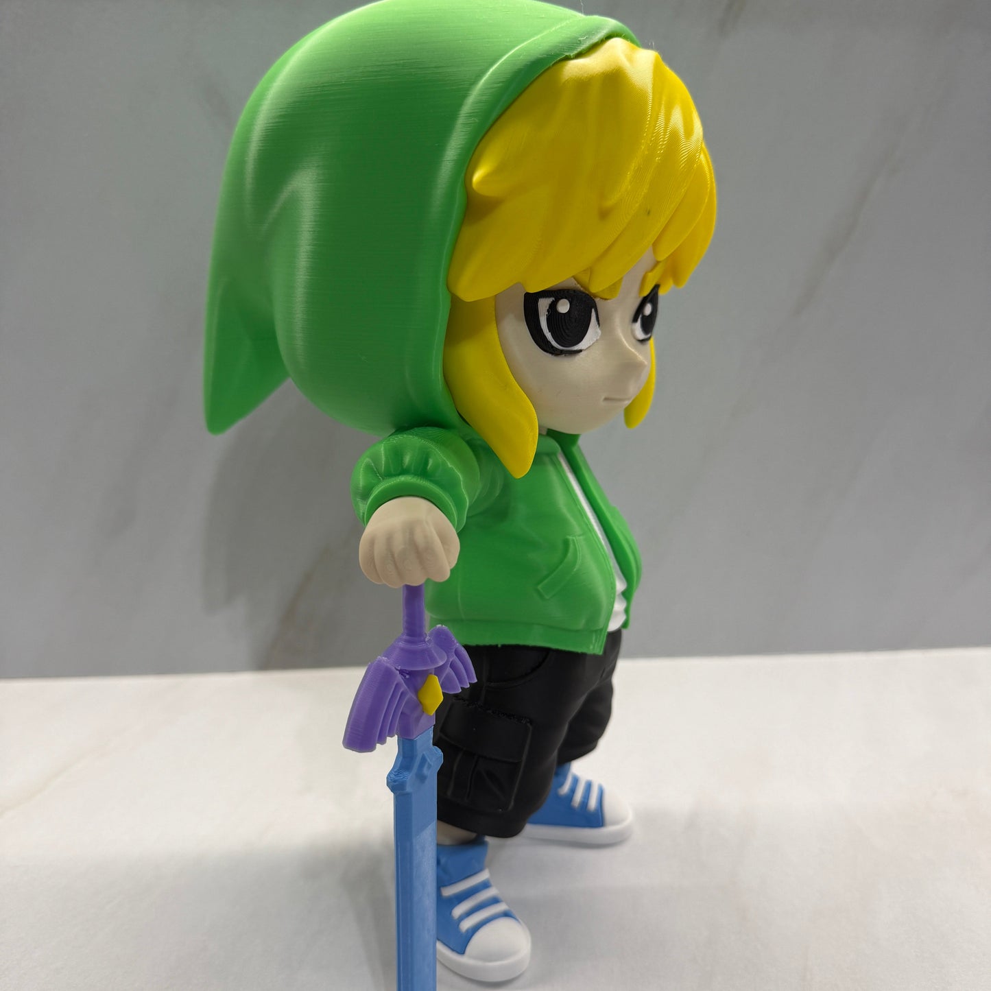 Toy figure of a character with yellow hair and green outfit holding a blue sword on a white background