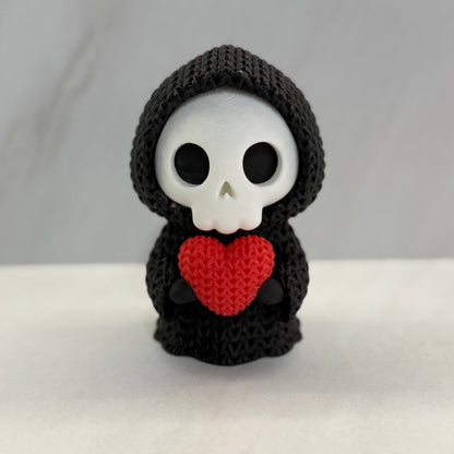 Crocheted skeleton toy with a red heart on a white background
